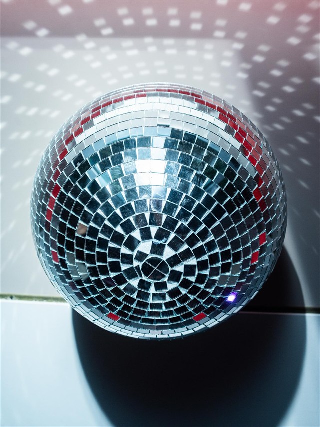 Globo espelhado espalhando pontos de luz pela parede.